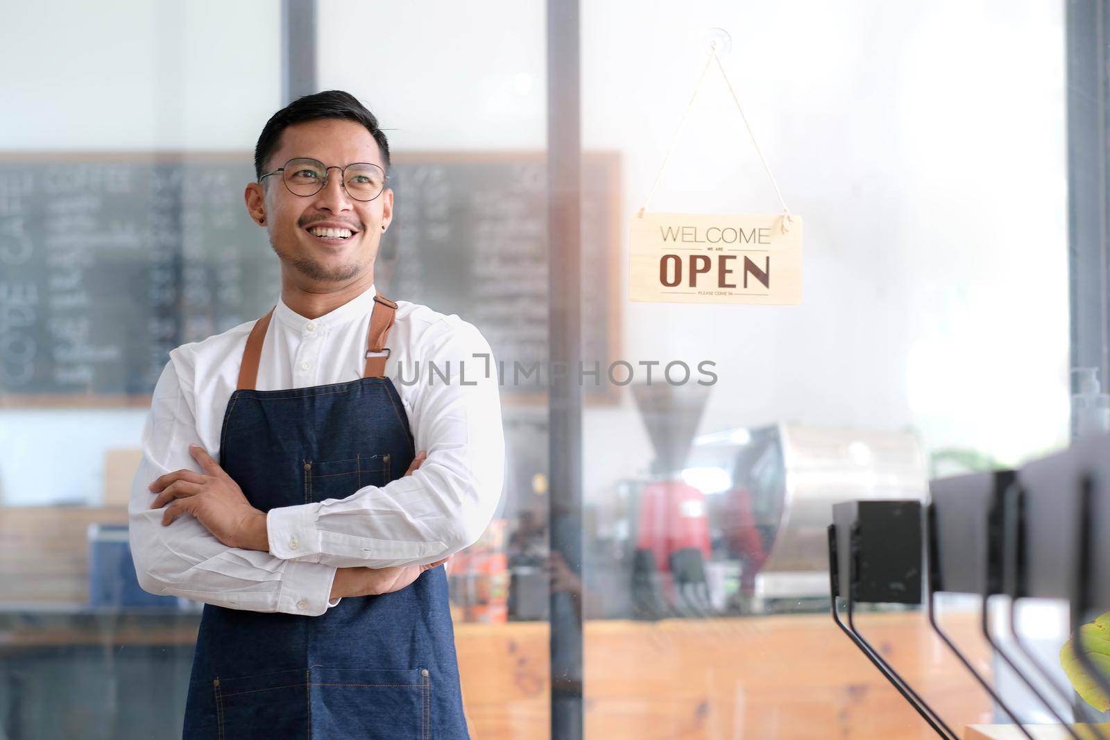 Startup successful small businessman owner sme stand with tablet smartphone in coffee shop restaurant. Portrait of asian tan man barista cafe owner. SME entrepreneur seller business concept by wichayada