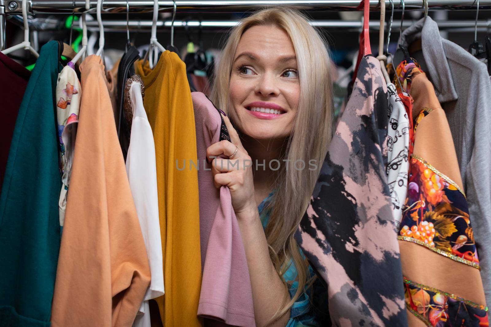 A happy woman shopping. The backstory of a clothing store. A thrilling and exciting shopping experience for every woman. . Blonde woman with straight long hair.