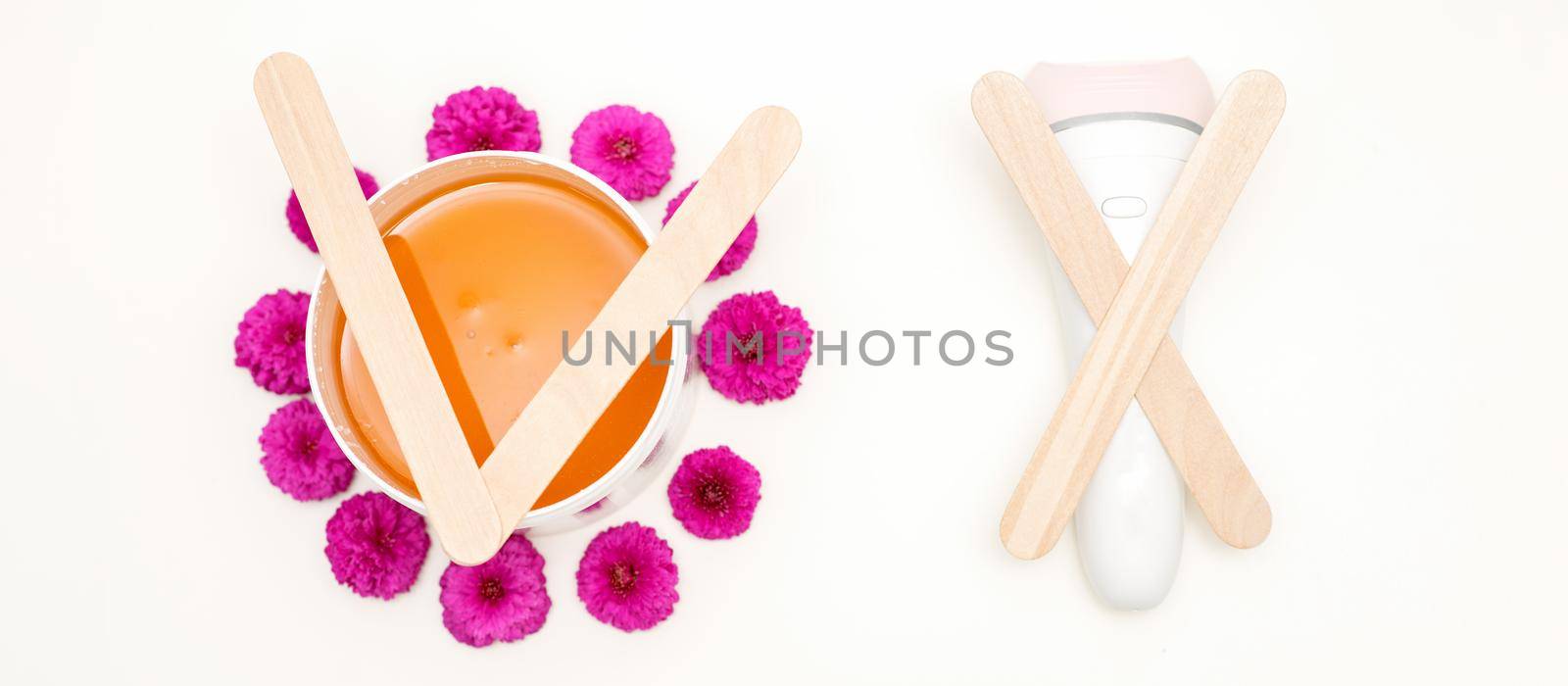 Waxing, depilation concept. Flat lay of the white cosmetic jar with sugar paste and epilator with wooden sticks lying on white background