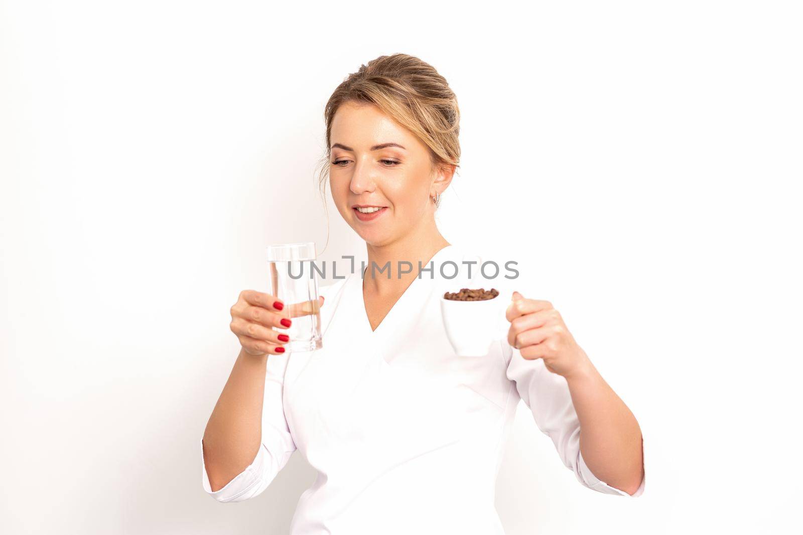 Coffee with water. The female nutritionist holds a cup of coffee beans and a glass of water in her hands on white background