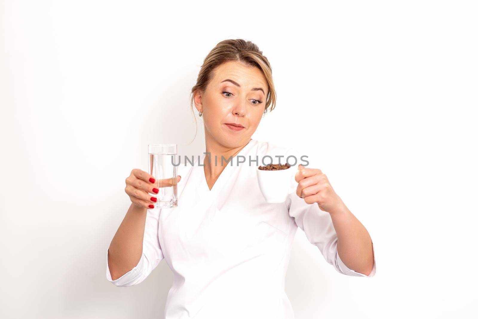Coffee with water. The female nutritionist holds a cup of coffee beans and a glass of water in her hands on white background