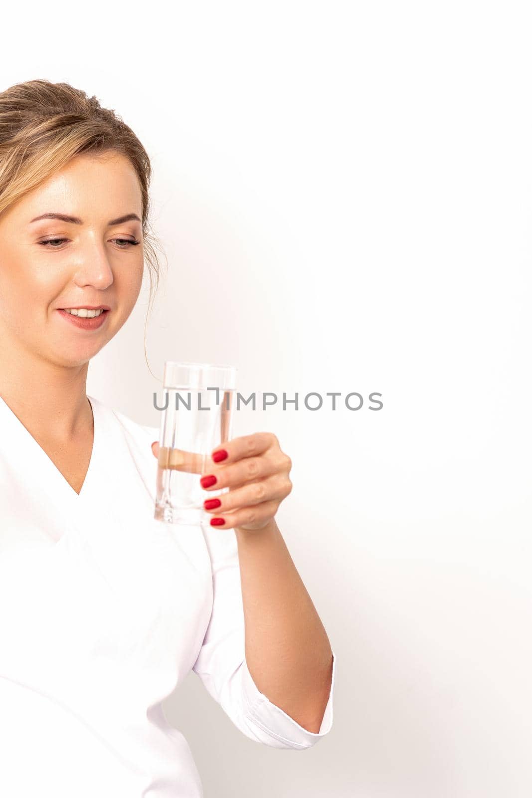 A glass of water. The female nutritionist holds a glass of water in her hand on white background. by okskukuruza