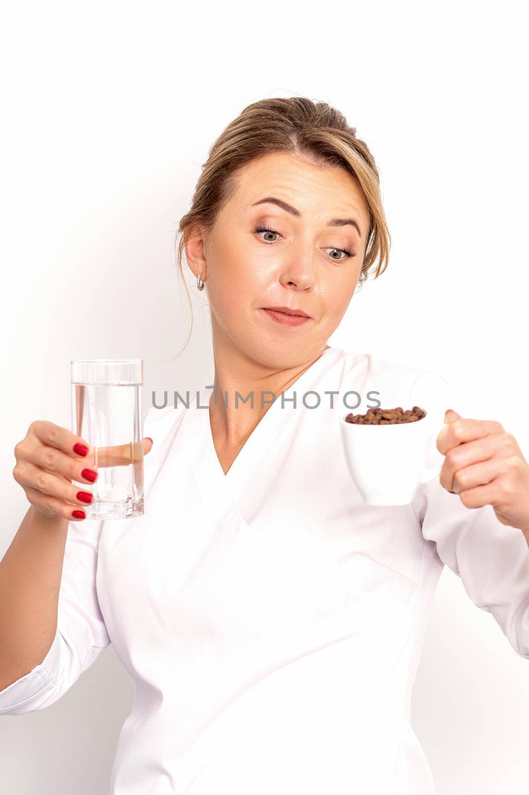 Coffee with water. The female nutritionist holds a cup of coffee beans and a glass of water in her hands on white background. by okskukuruza