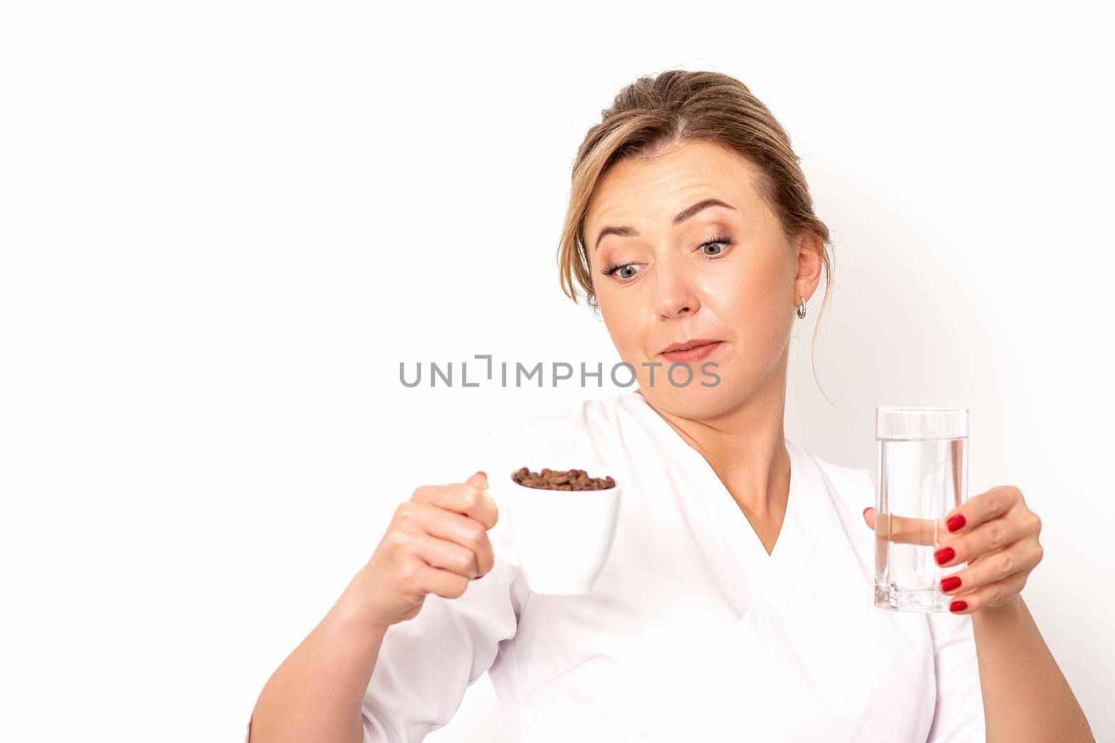Coffee with water. The female nutritionist holds a cup of coffee beans and a glass of water in her hands on white background