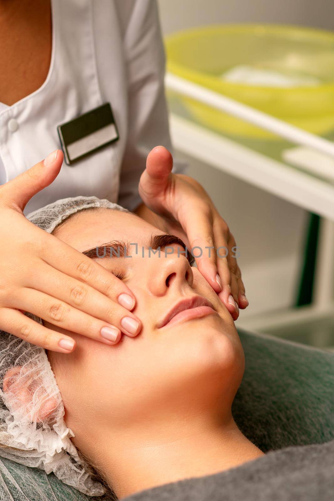 Face massage. Beautiful caucasian young white woman having a facial massage with closed eyes in a spa salon