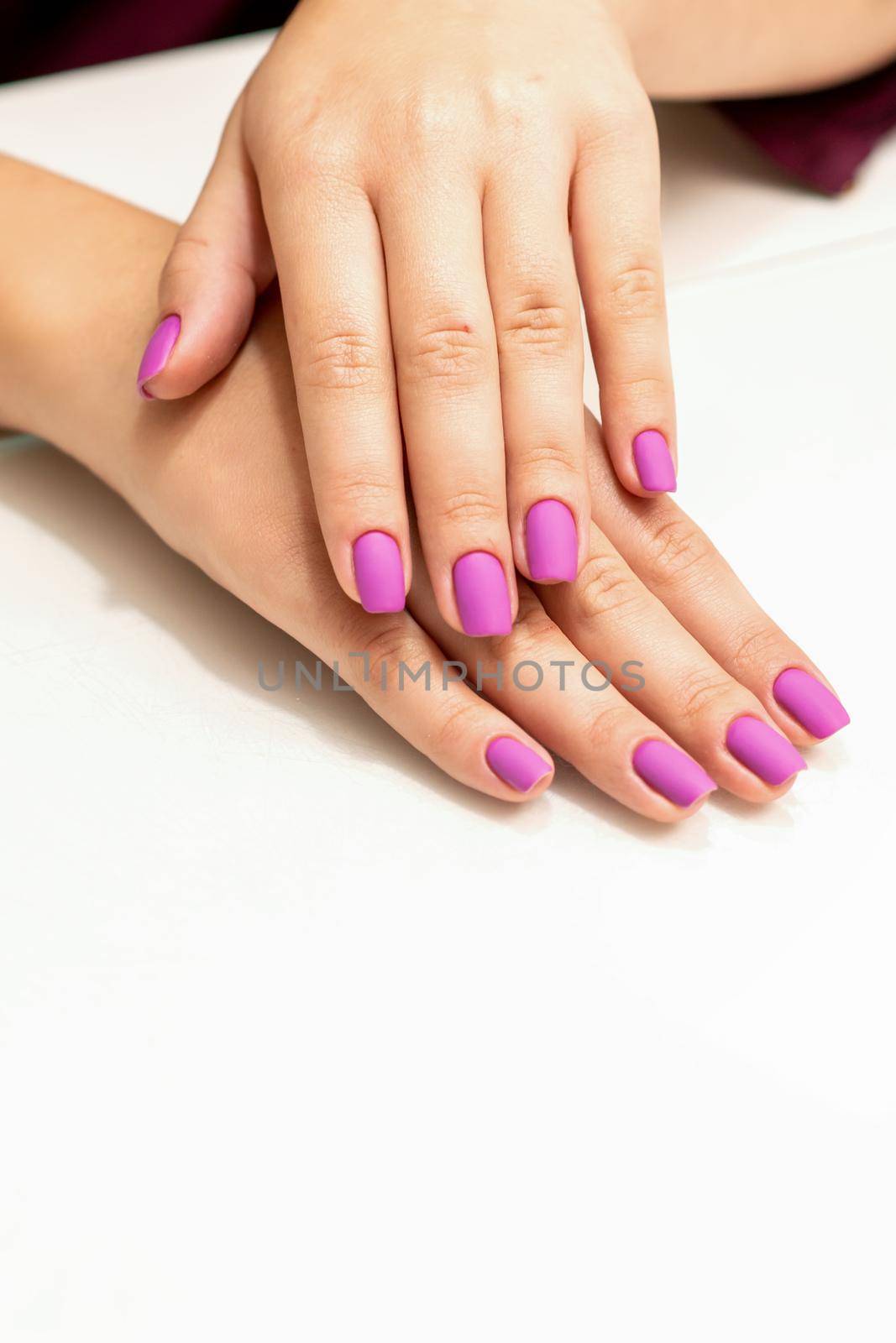 Beautiful manicure with purple, pink nail polish on young caucasian female hands. by okskukuruza