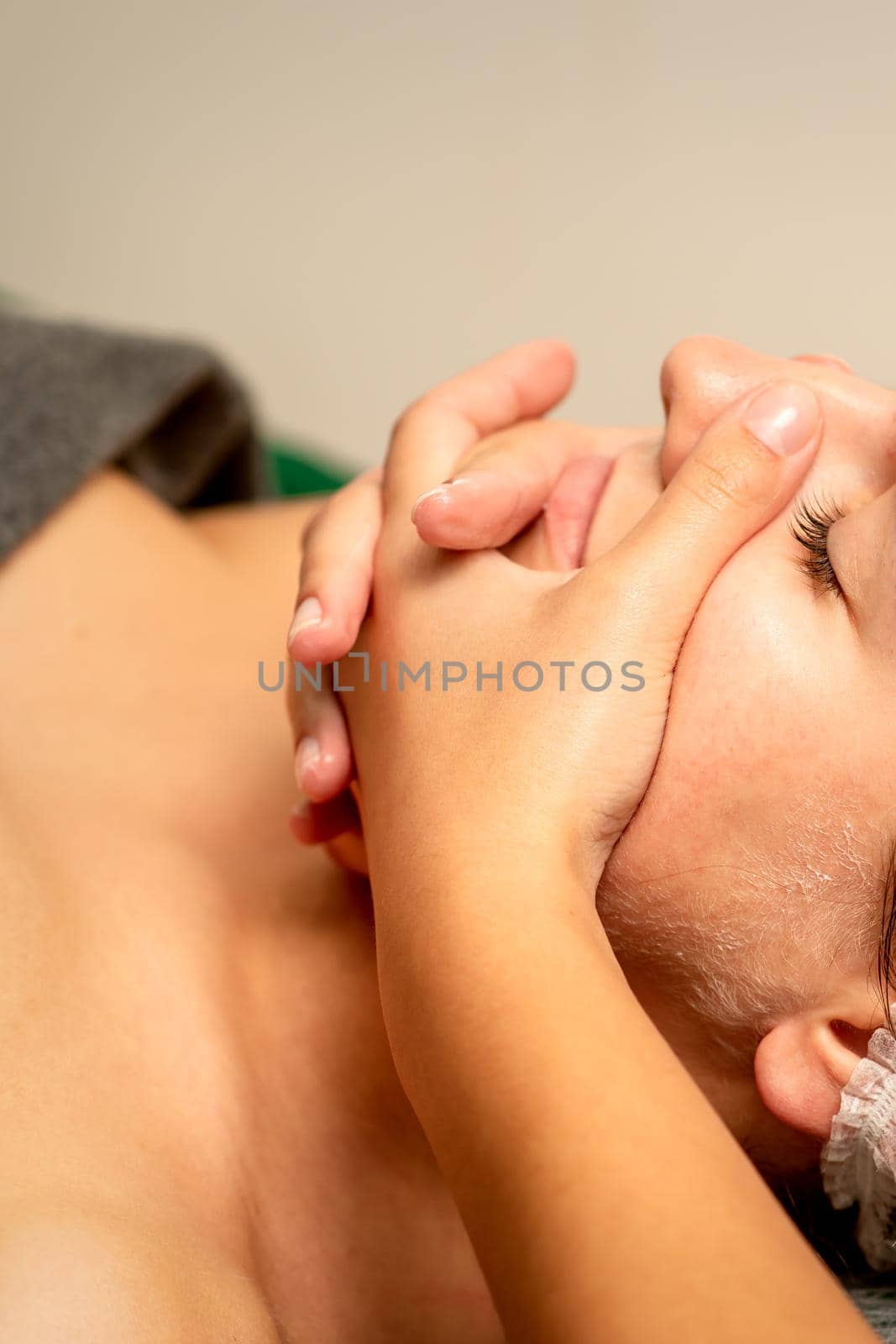 Face massage. Beautiful caucasian young white woman having a facial massage with closed eyes in a spa salon. by okskukuruza