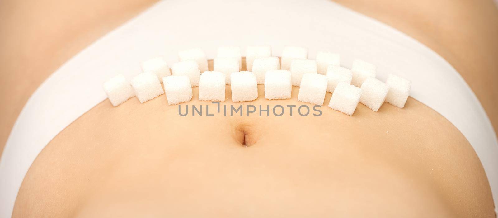 The concept of epilation, waxing, and intimate hygiene. Sugar cubes lying in a row on the bikini zone of a young white woman, close up