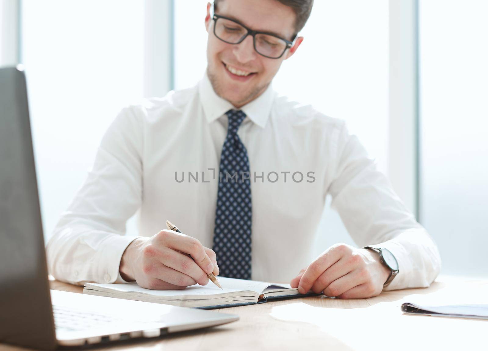 Closeup of business man writing form on clipboard at office by Prosto