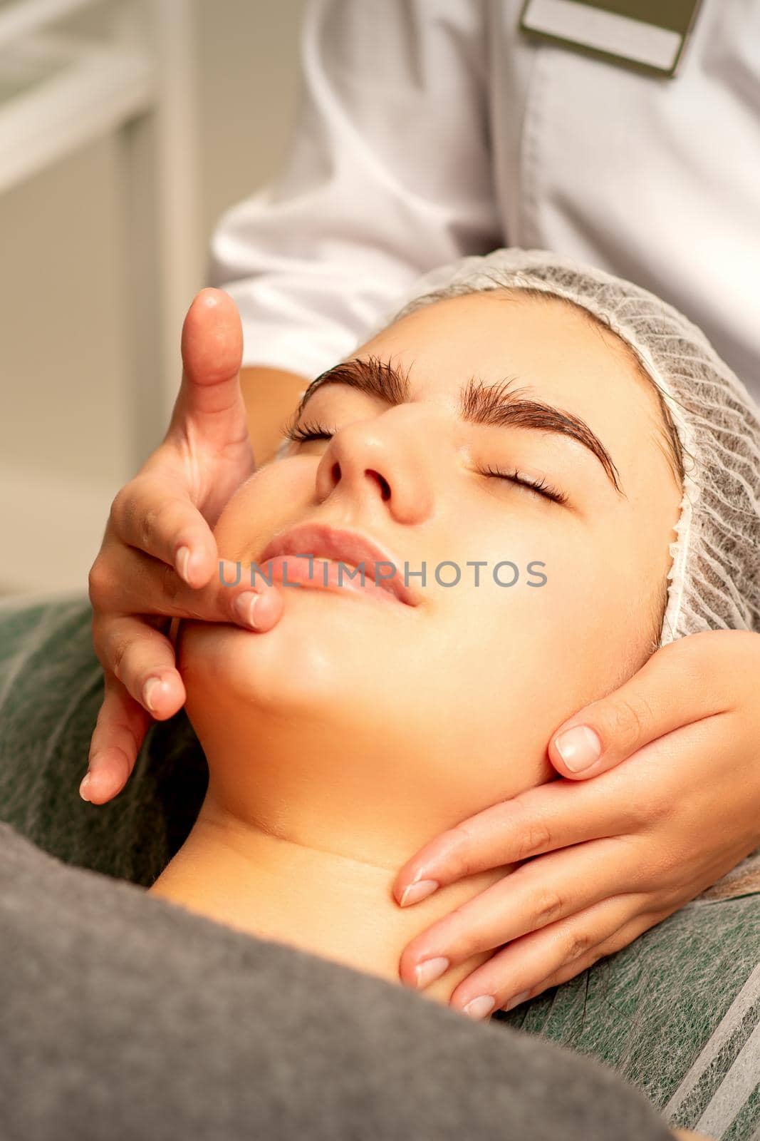 Face massage. Beautiful caucasian young white woman having a facial massage with closed eyes in a spa salon