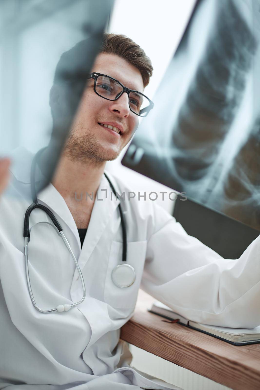 Male doctor in glass radiologist examines x-rays in a medical office.