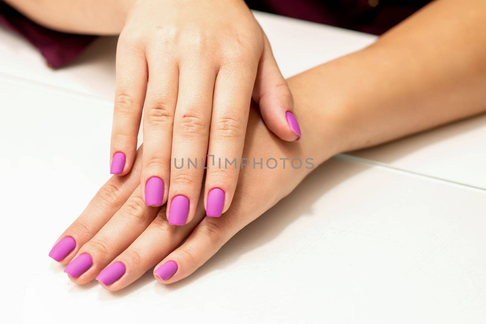 Beautiful manicure with purple, pink nail polish on young caucasian female hands