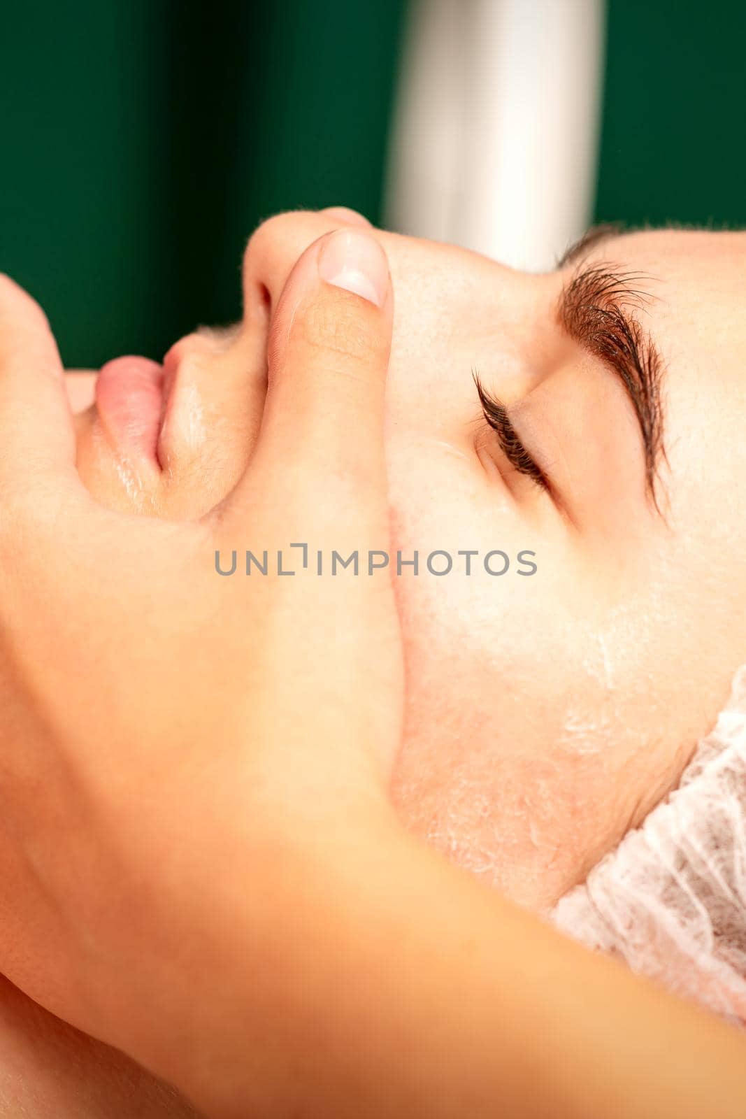 Face massage. Beautiful caucasian young white woman having a facial massage with closed eyes in a spa salon. by okskukuruza