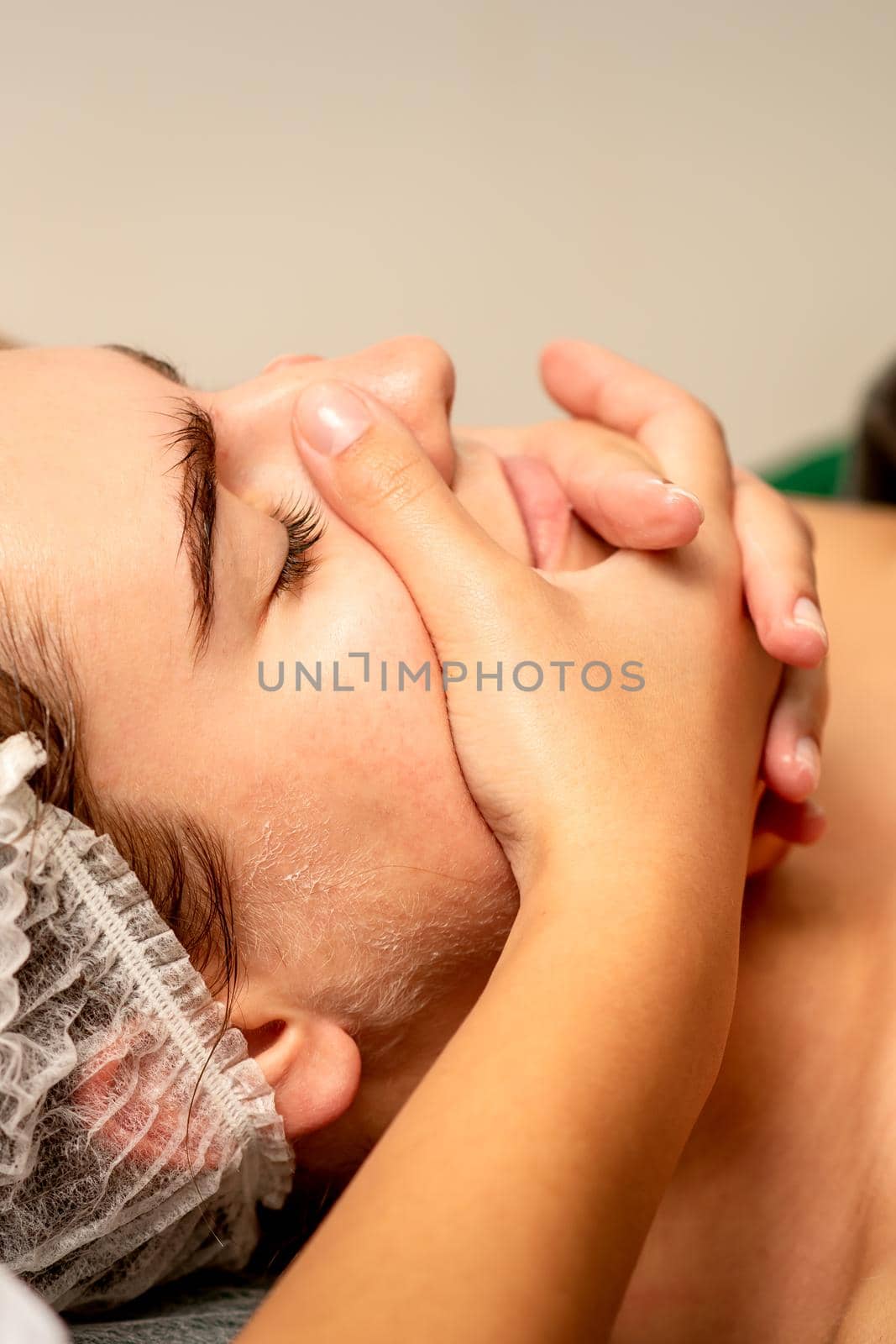 Face massage. Beautiful caucasian young white woman having a facial massage with closed eyes in a spa salon. by okskukuruza