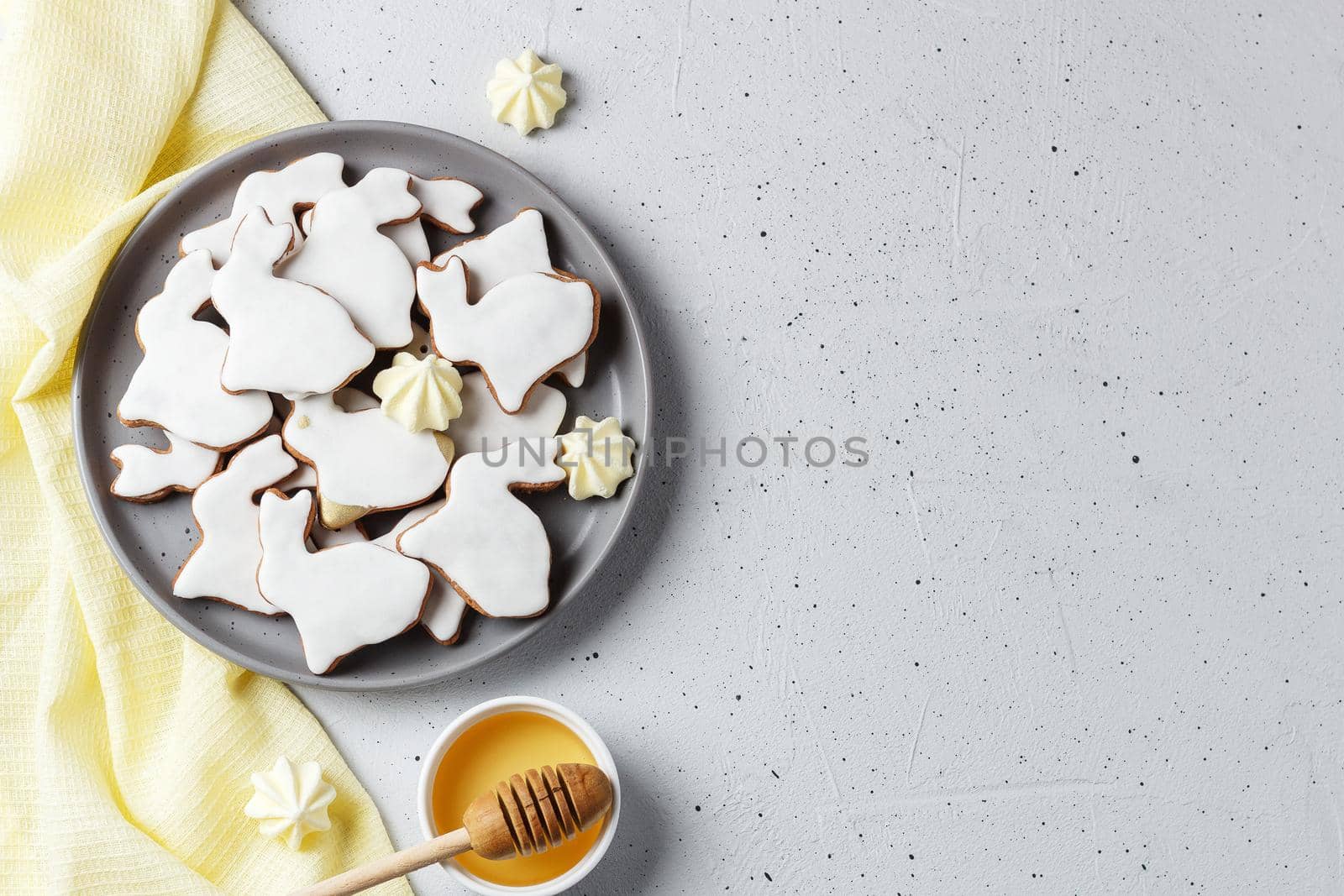 Easter cookies in the form of a rabbit on a gray plate with honey and yellow textiles on a gray background. copy space by lara29