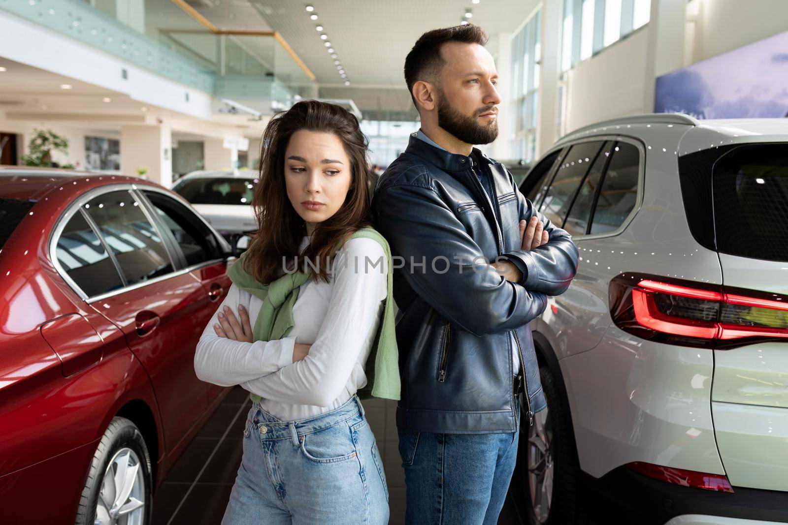 frustrated man and woman at car dealership can't agree on buying a new car.