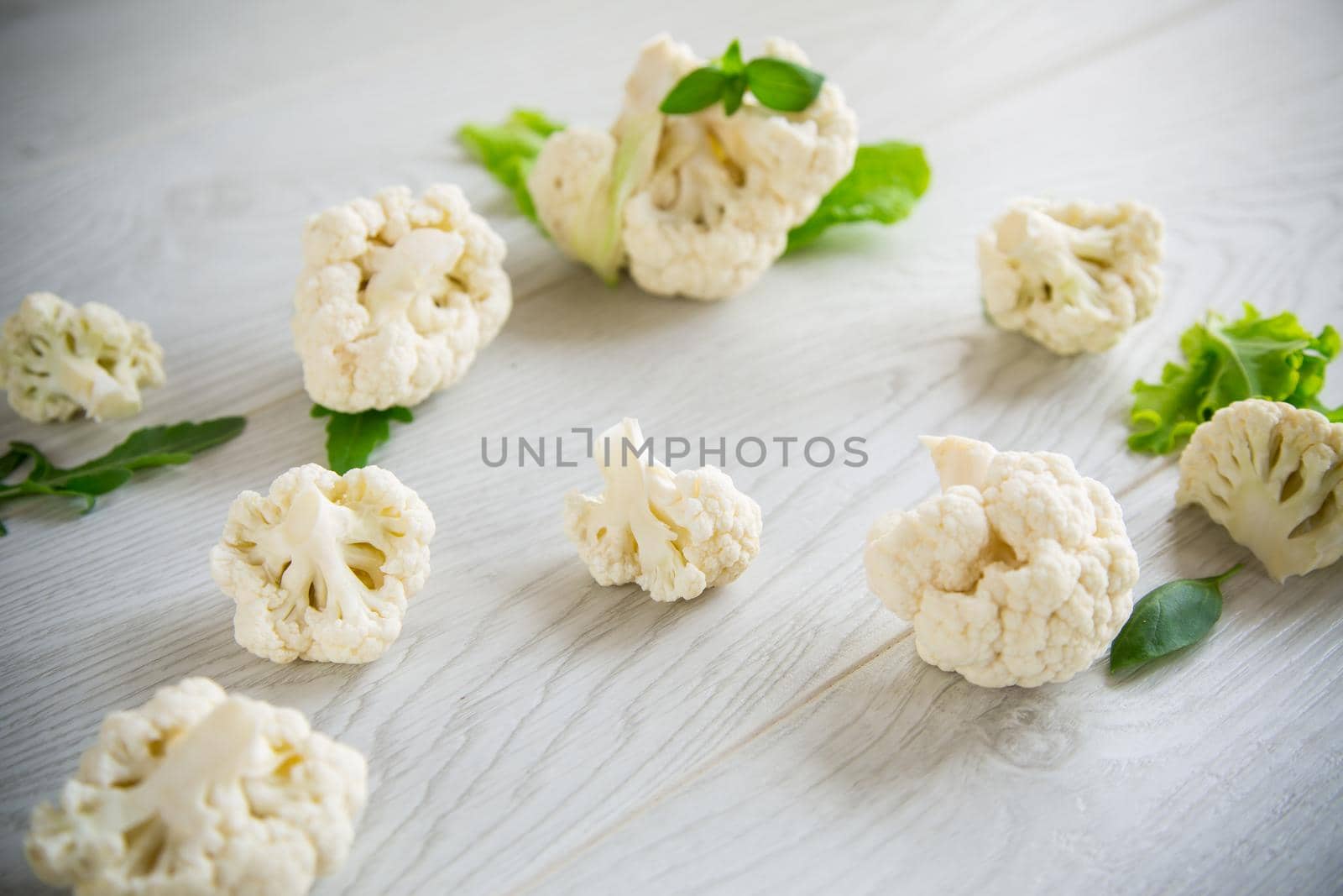 inflorescences of small raw cauliflower on a light wooden table