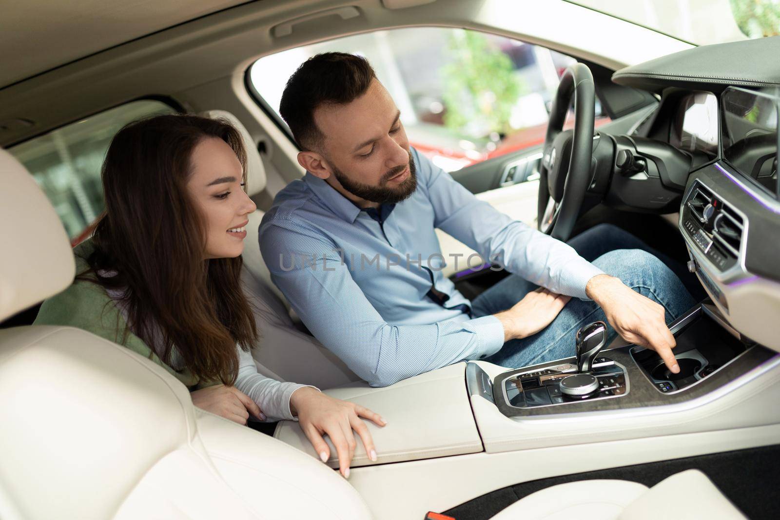 young couple exploring additional options when buying a new car at a car dealership.