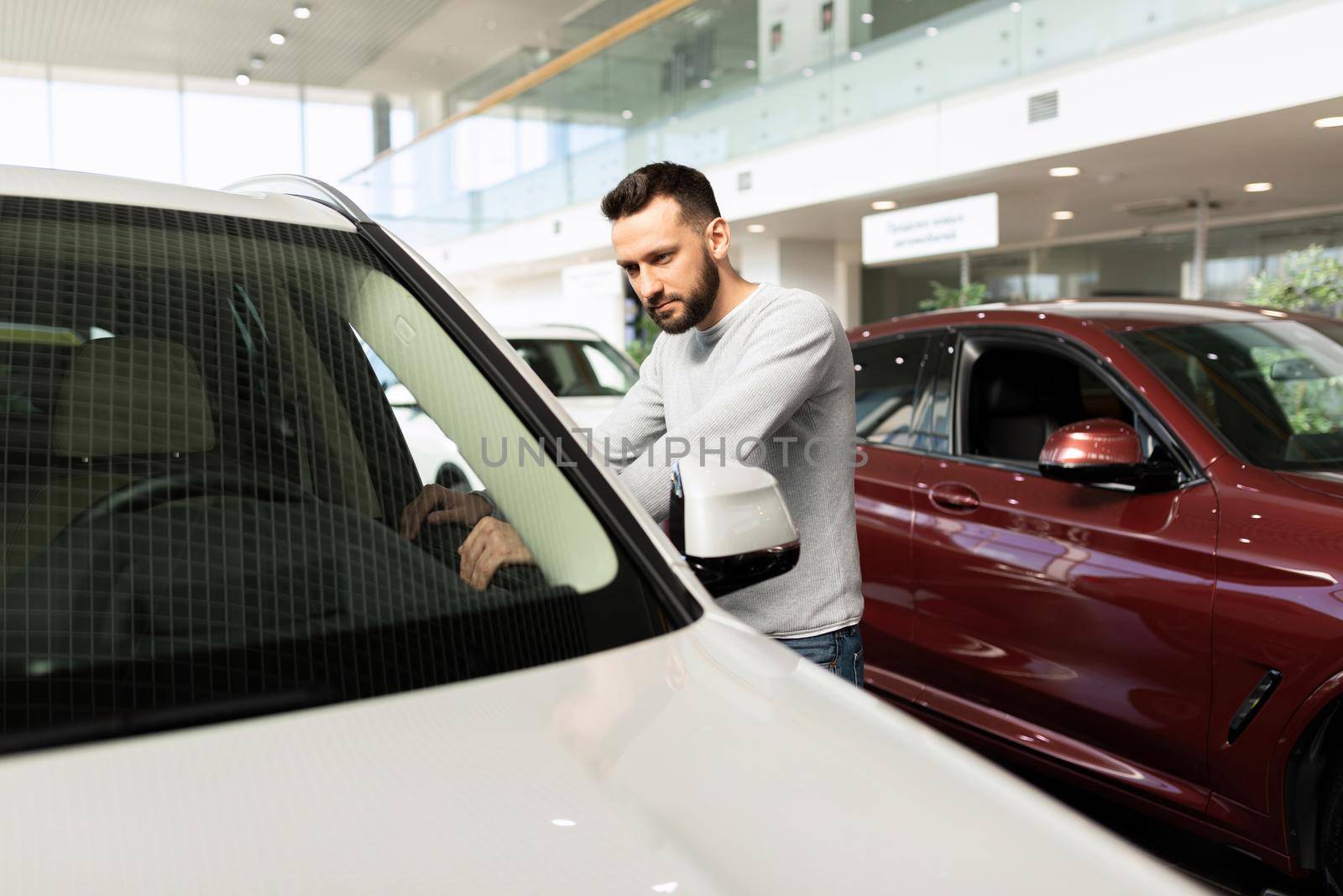 a man examines a car in a car dealership.
