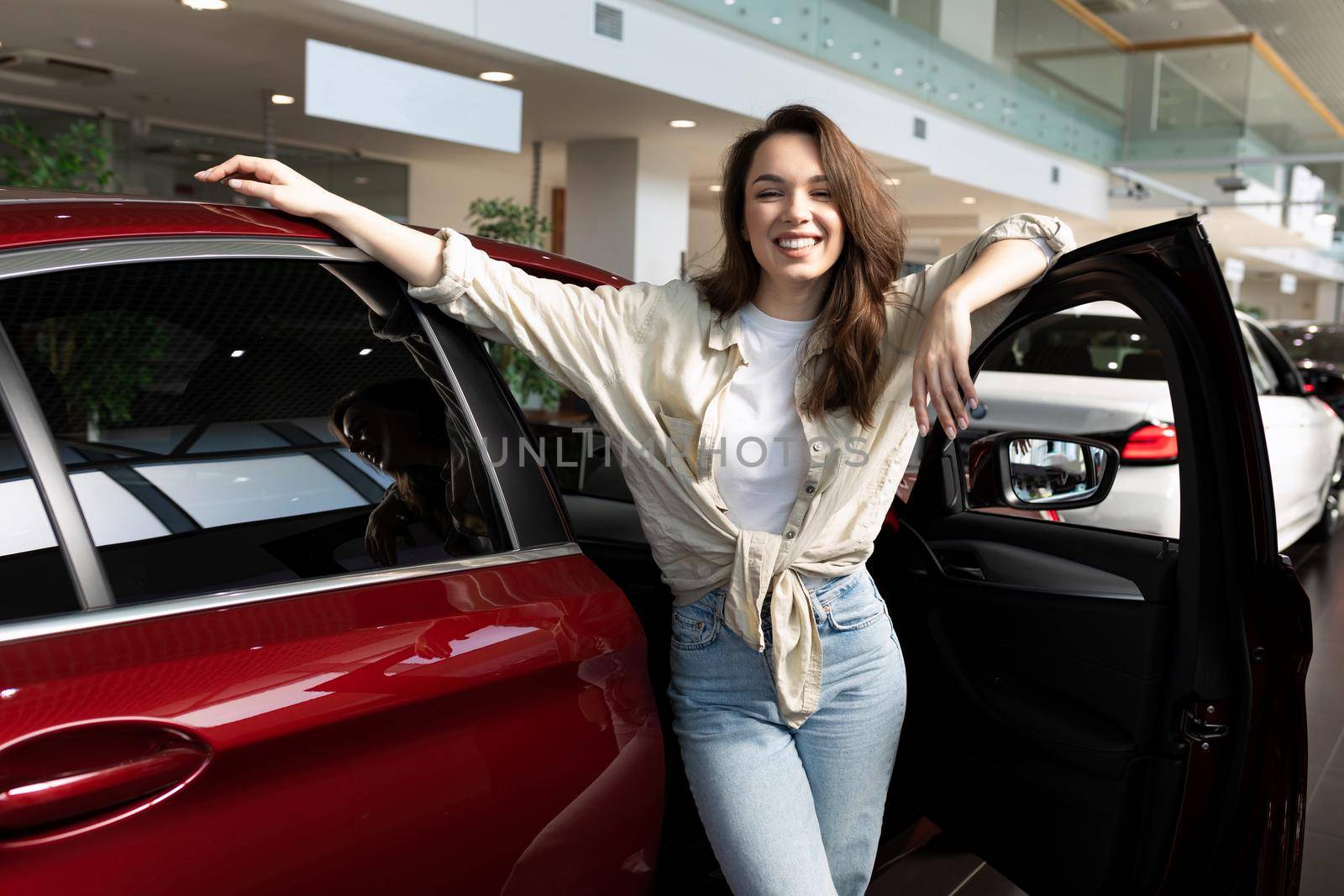 a young woman draws up a deal to buy a new car and insure it at a car dealership.