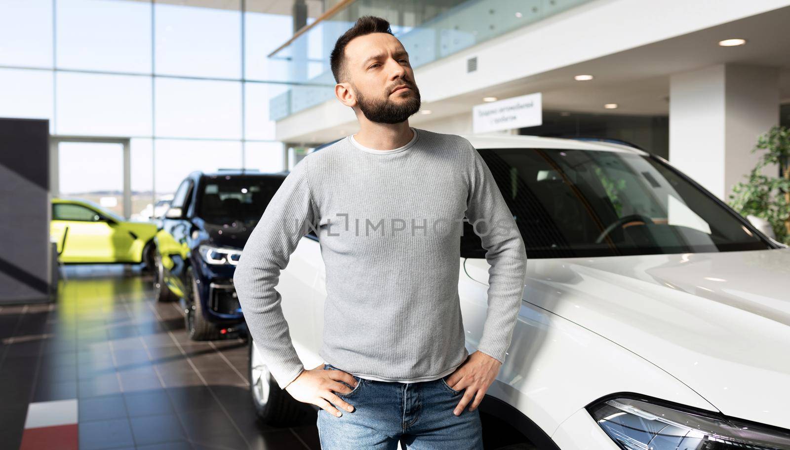 middle-aged man chooses a new car in a car dealership.