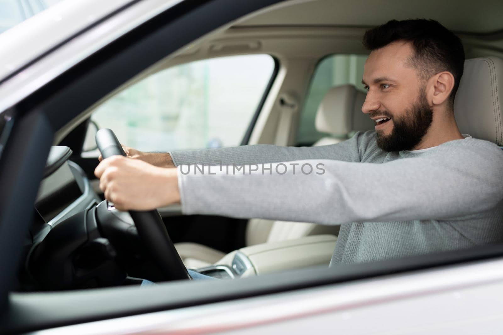 novice driver behind the wheel of a new car looks ahead with a smile.