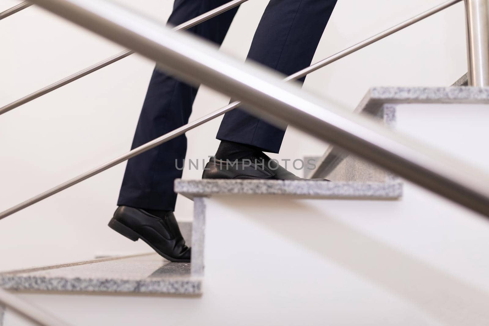 a businessman moves up the steps to the top, close-up of the steps and male legs.