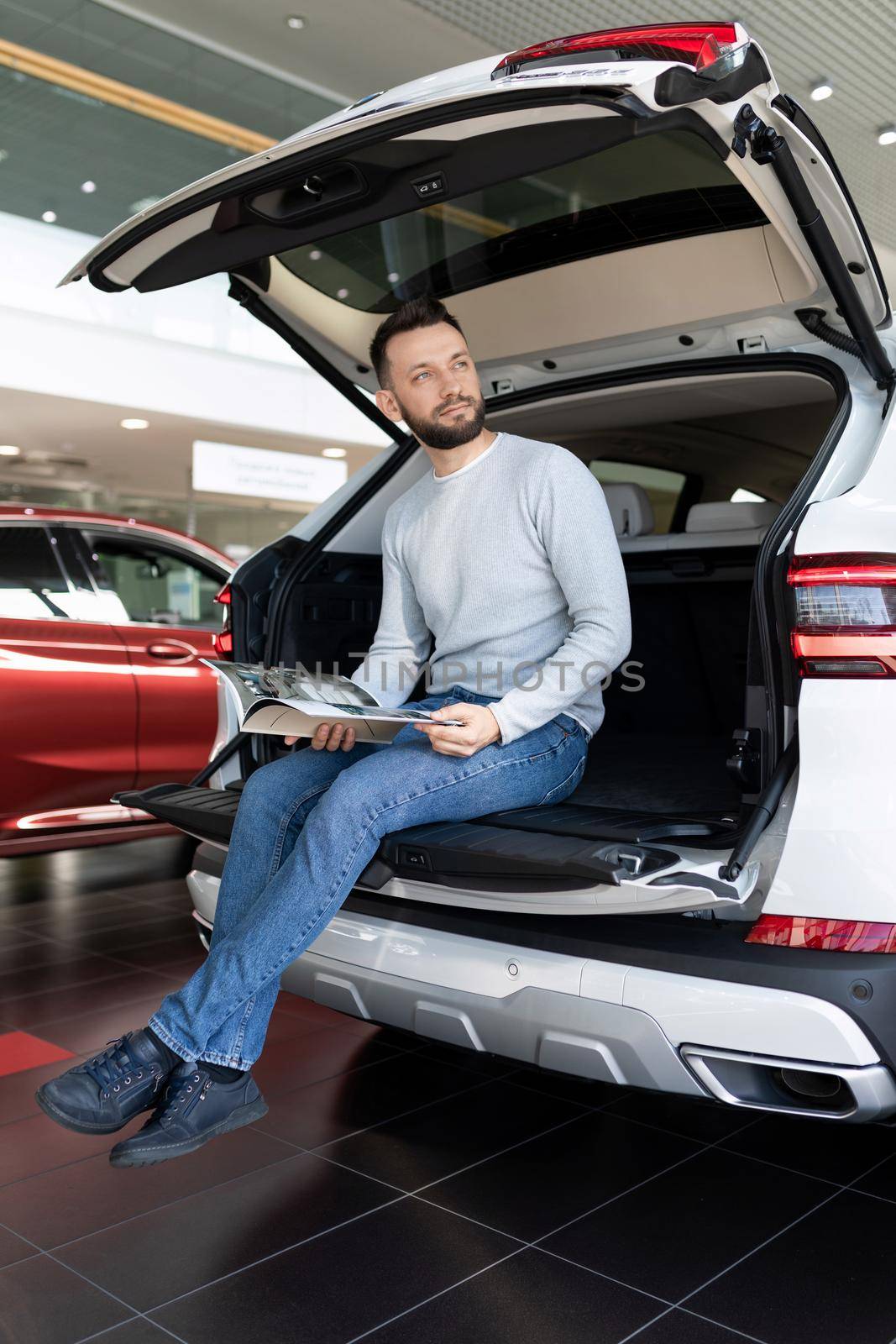 A man sits in the trunk of an SUV and dreams of buying it.
