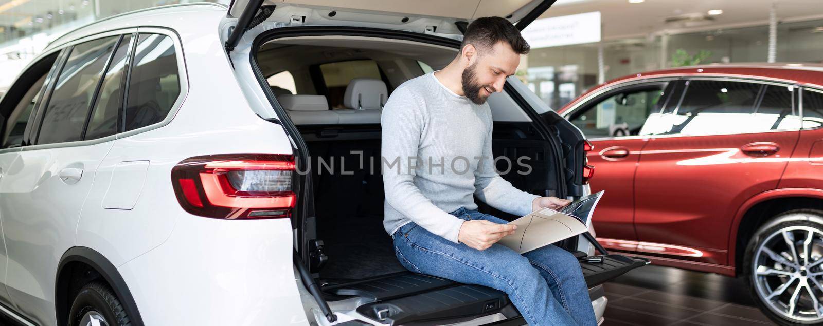 a man buys a new car and draws up an insurance policy for it at a car dealership.