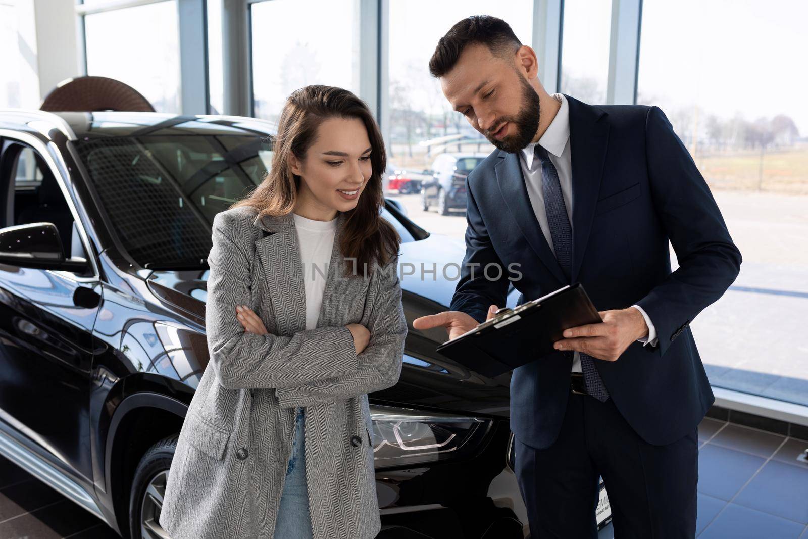 an employee of a car shop draws up documents for a new car for a woman buyer by TRMK