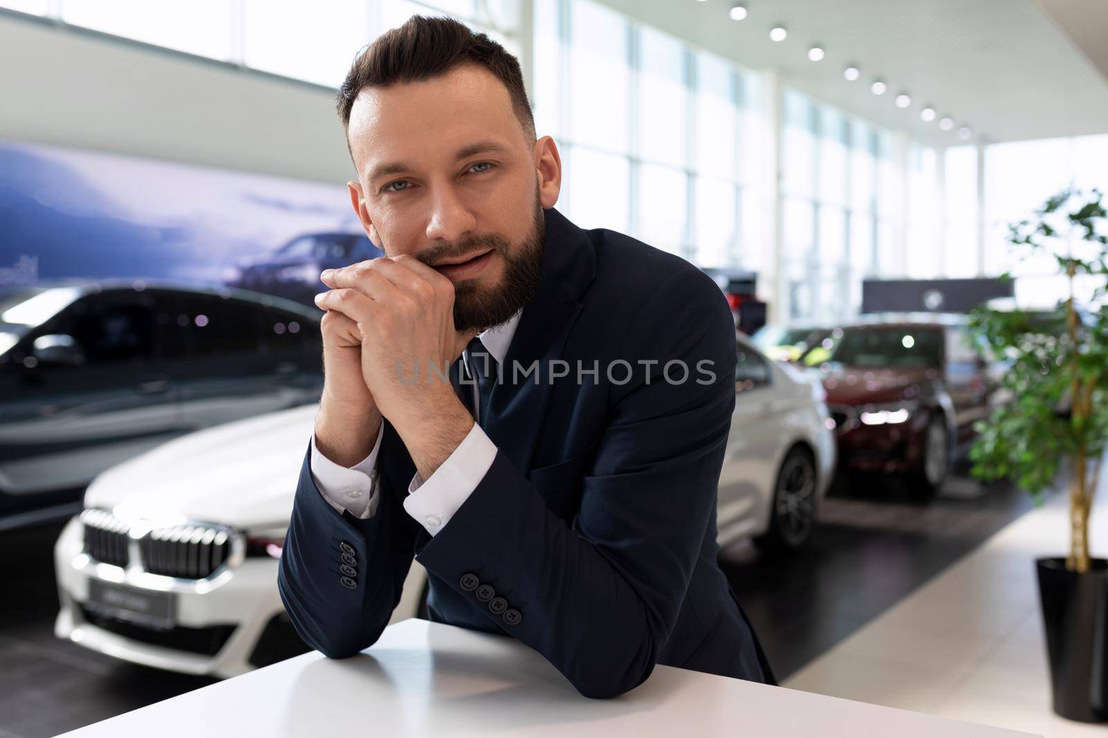 portrait of a businessman in the car showroom of a car dealership.