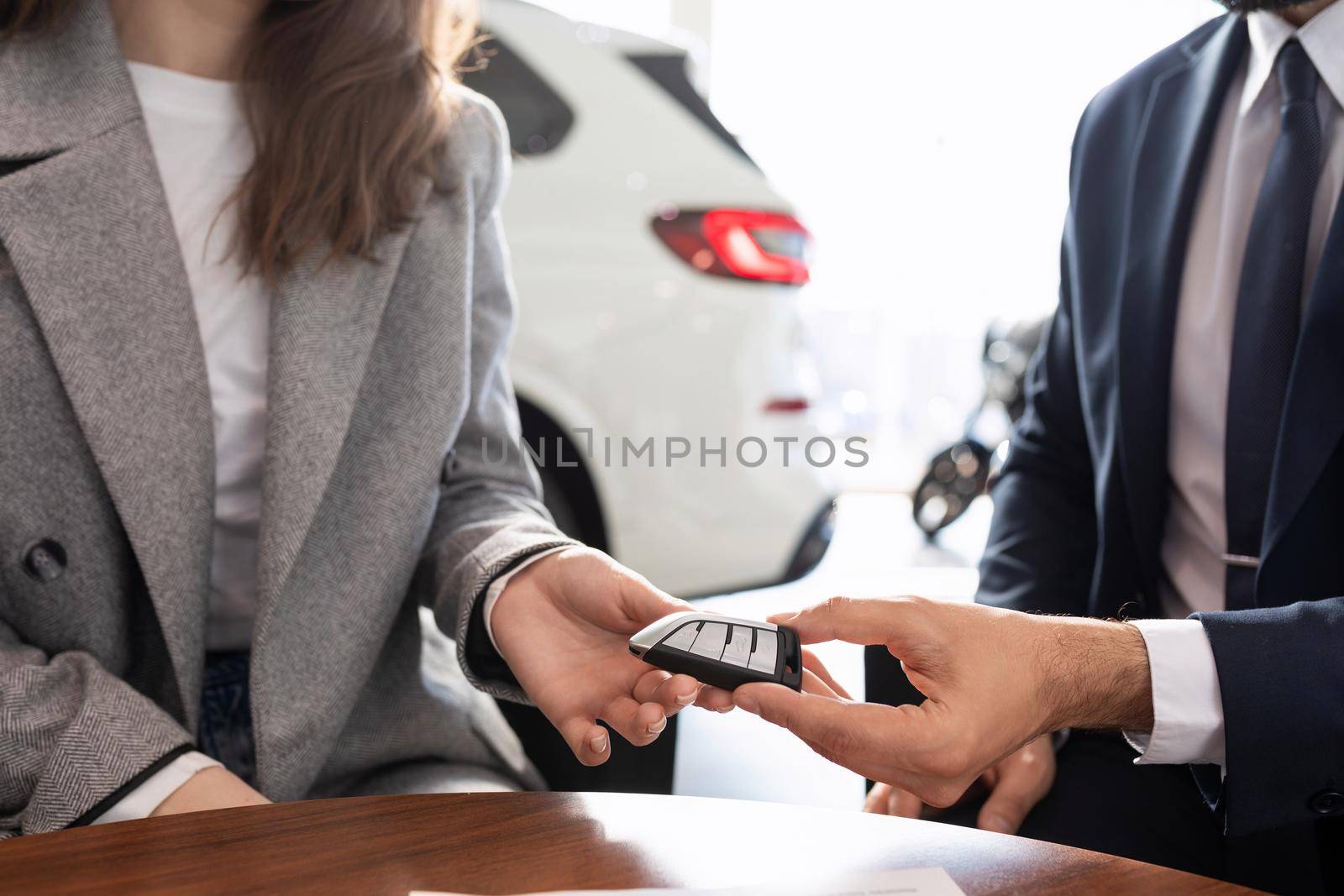 the seller in the car dealership gives the key to the new car to the buyer.