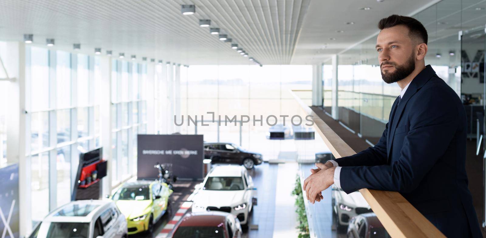 portrait of a car business owner against the backdrop of a car dealership.