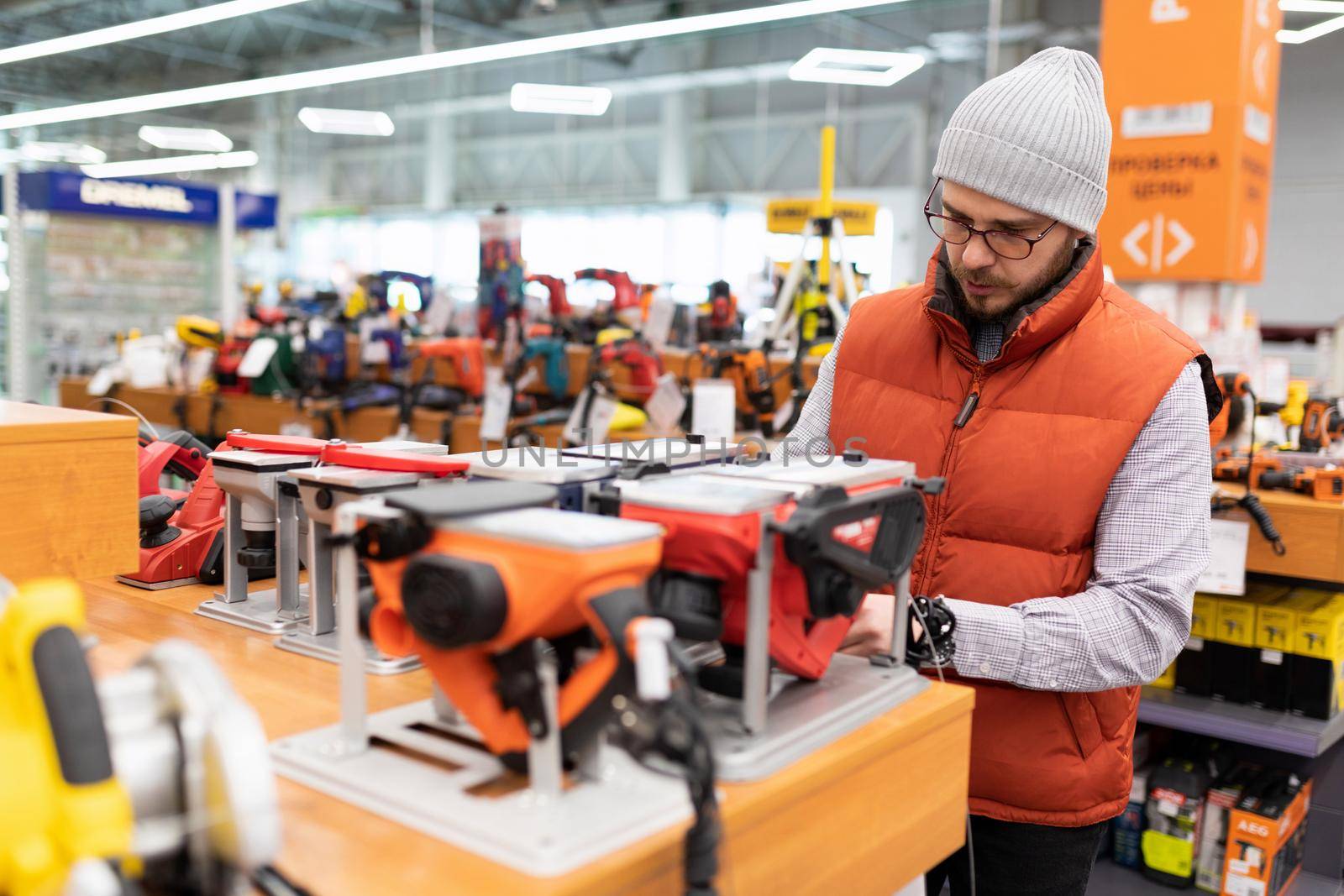 a man in a supermarket in the department of electrical goods chooses an electric planer.