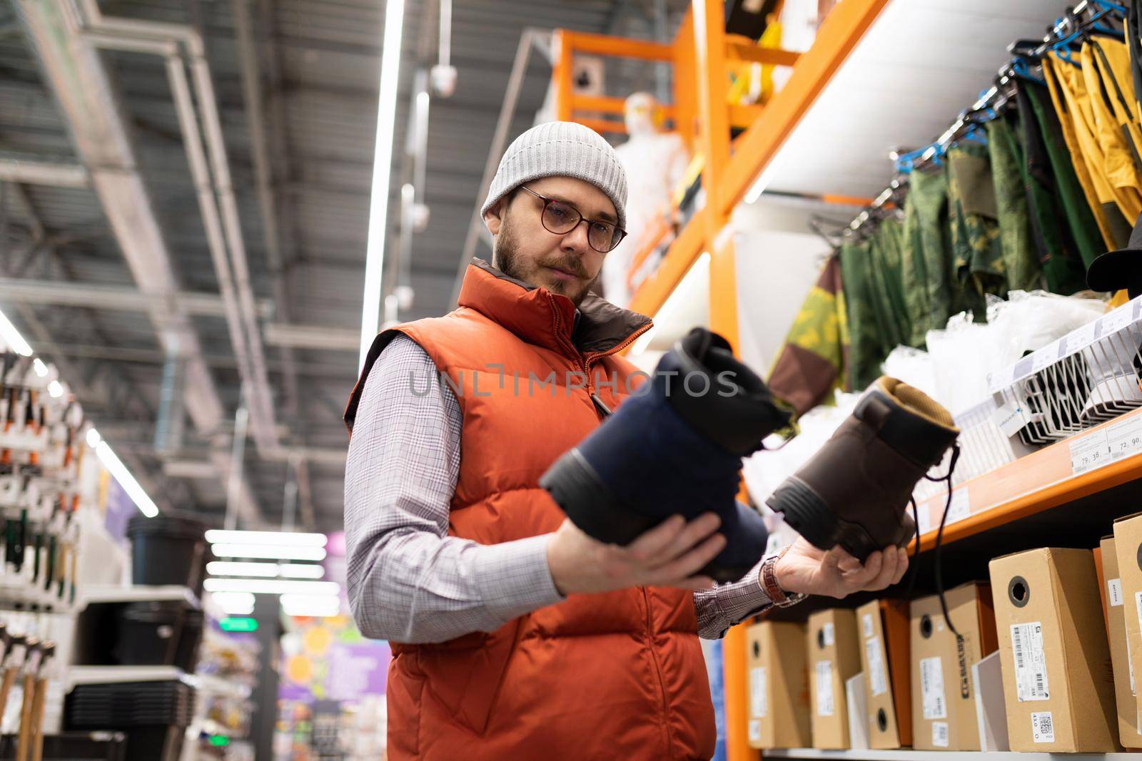 buyers a man in a hardware store chooses shoes for work at a construction site.