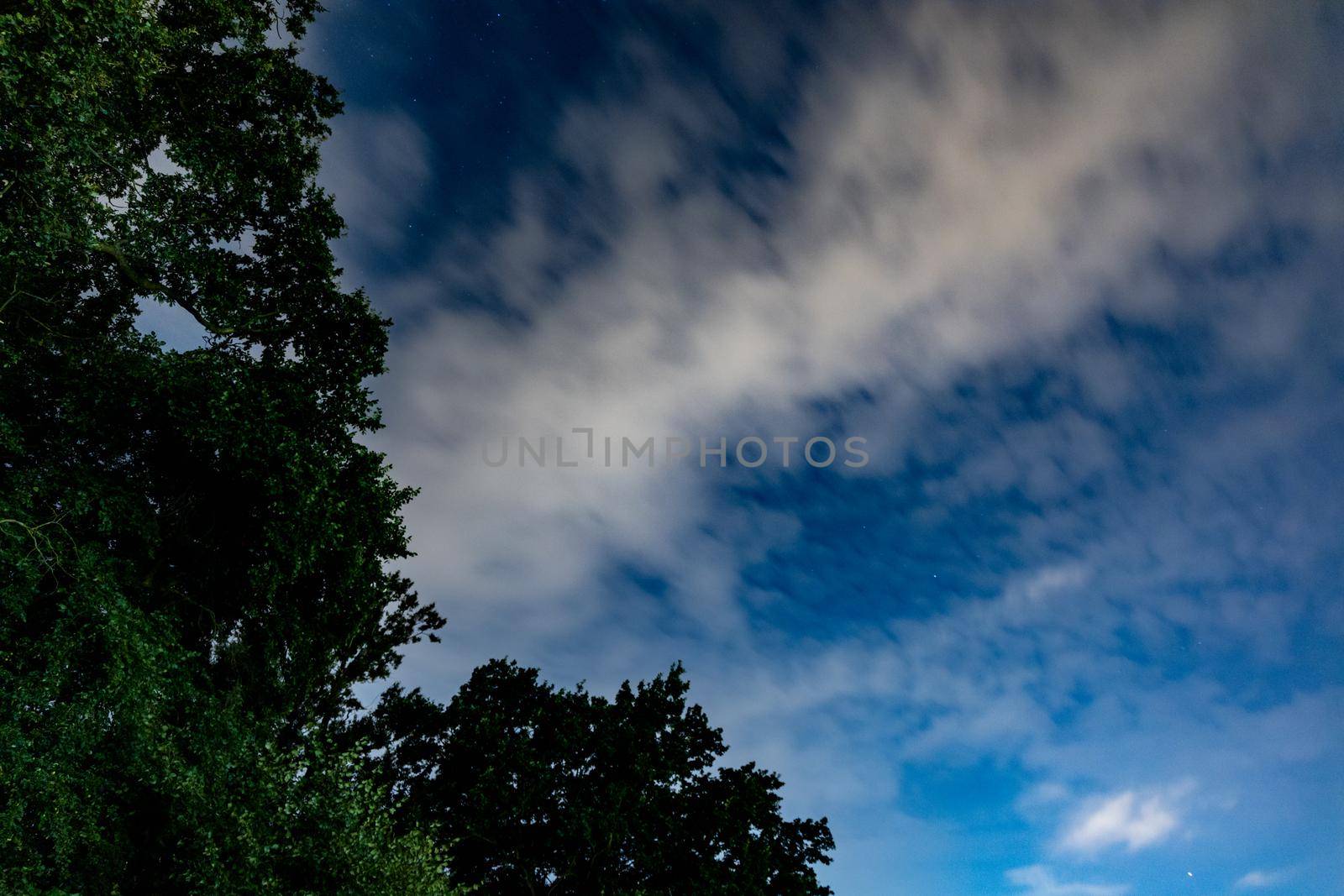 Dark blue sky on long exposure with moving clouds at night 