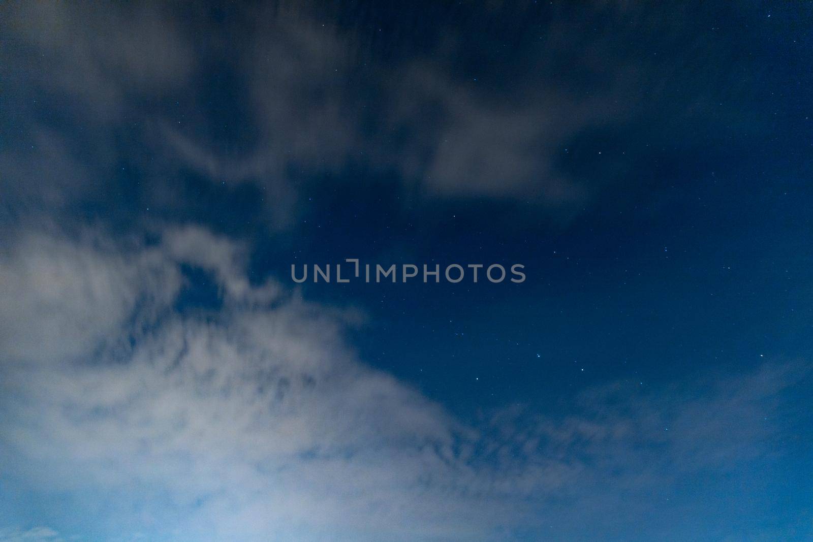 Dark blue sky on long exposure with moving clouds at night 