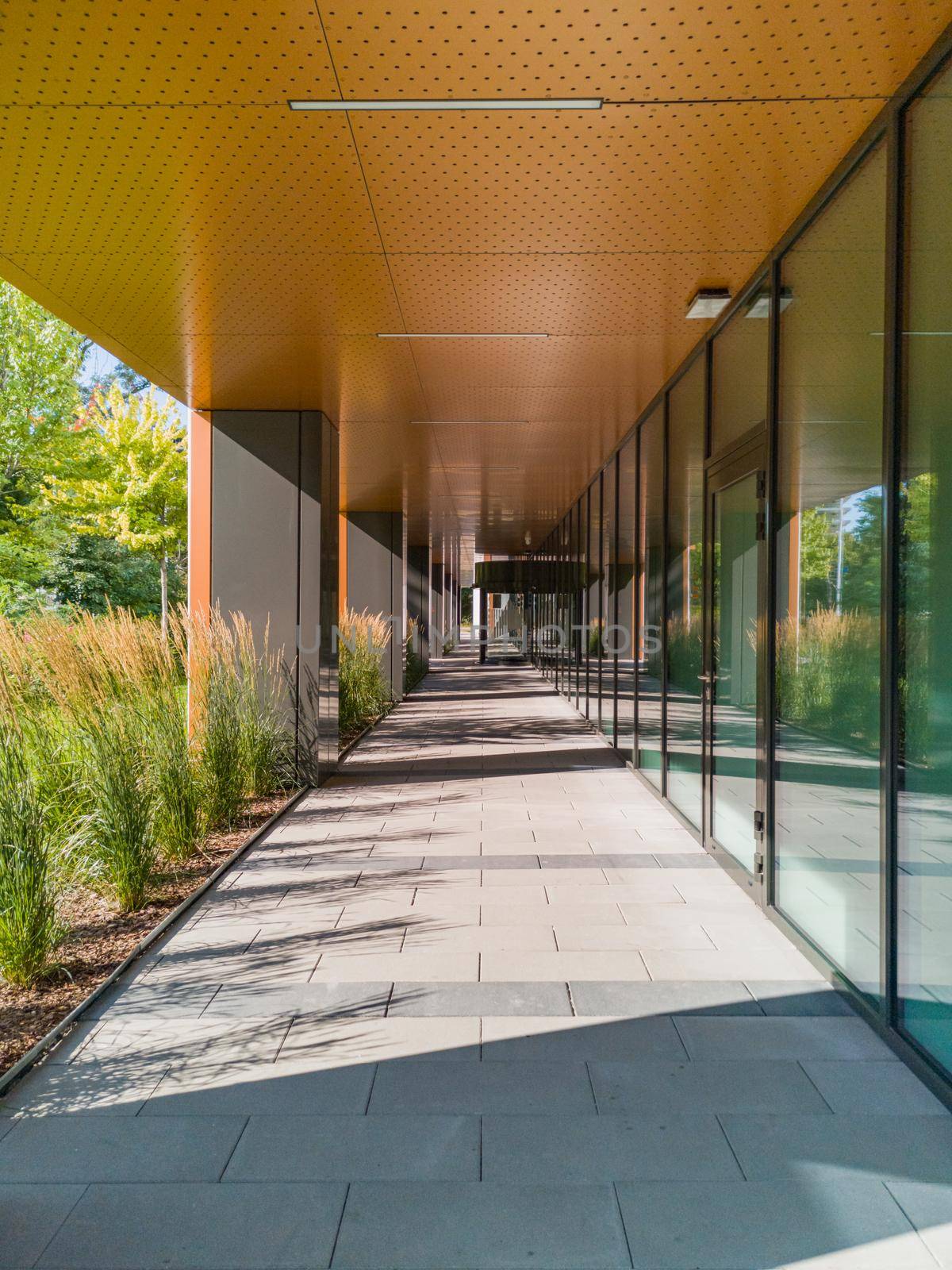 Long tunnel with pillars next to new modern corporate building