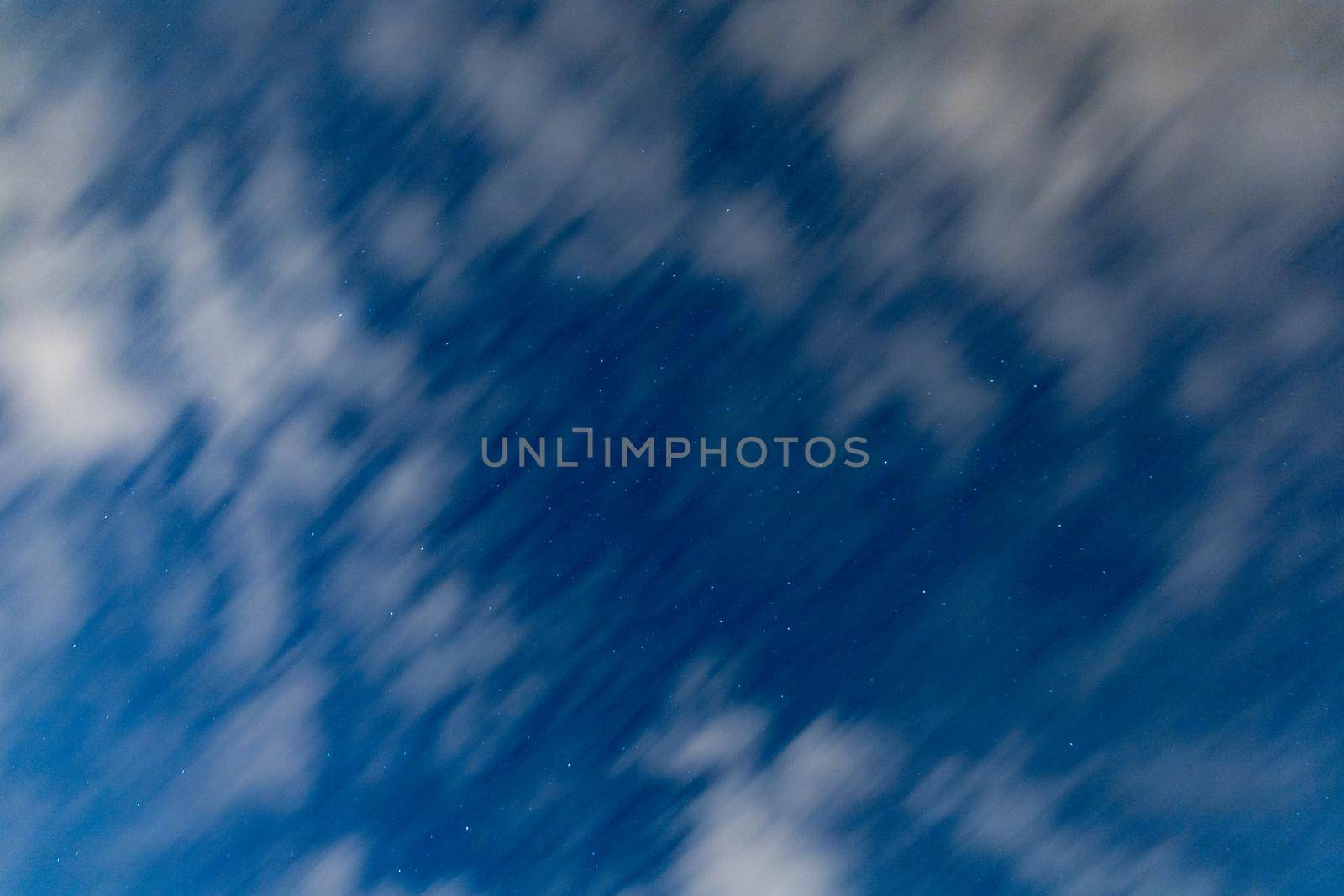 Dark blue sky on long exposure with moving clouds at night 