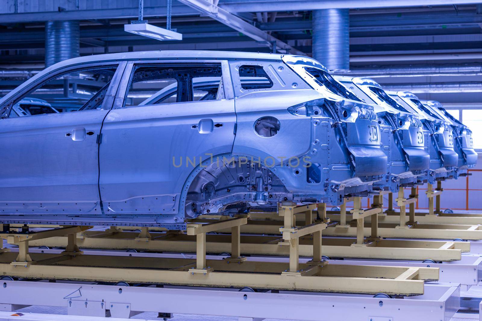 Photo of automobile production line. Welding car body. Modern car assembly plant. Auto industry. High-tech factory. Blue tone.