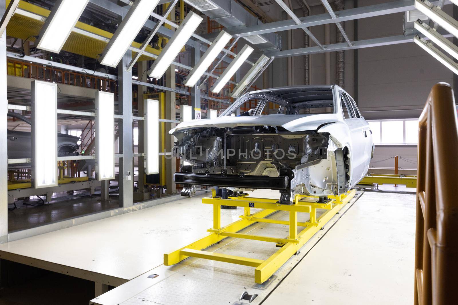 Car bodies are on assembly line. Factory for production of cars. Modern automotive industry. A car being checked before being painted in a high-tech enterprise.