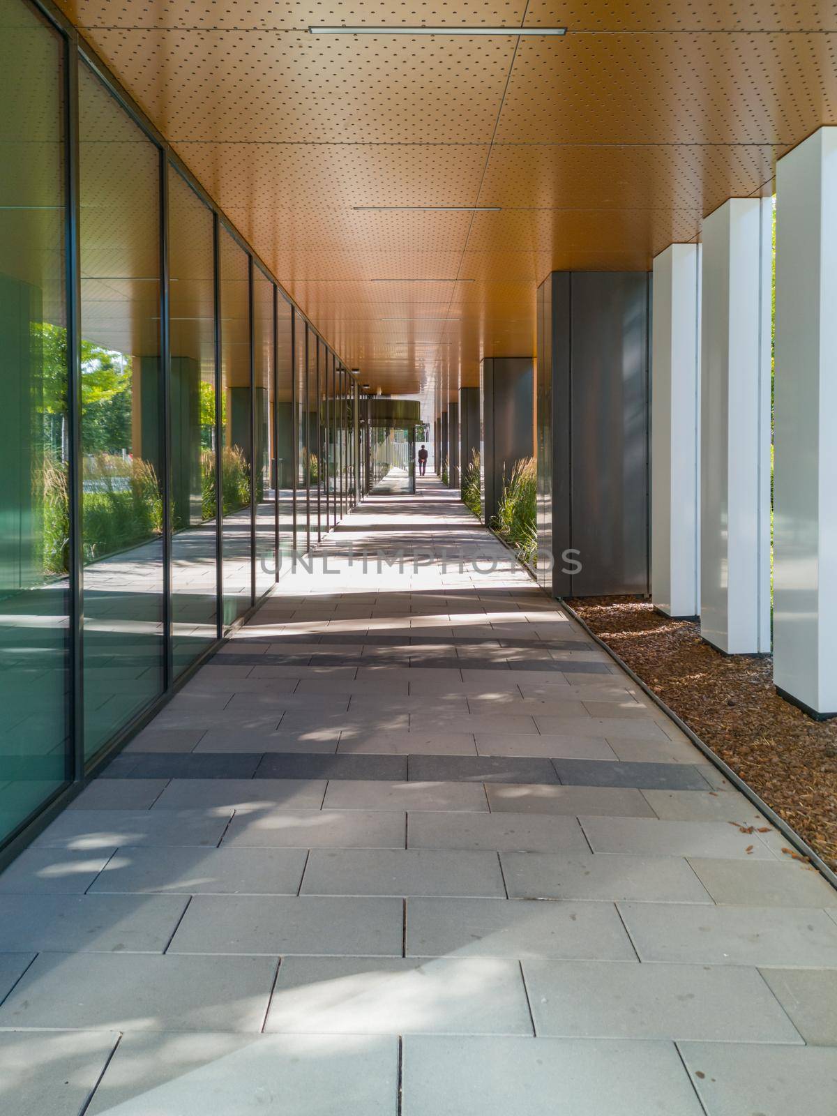 Long tunnel with pillars next to new modern corporate building