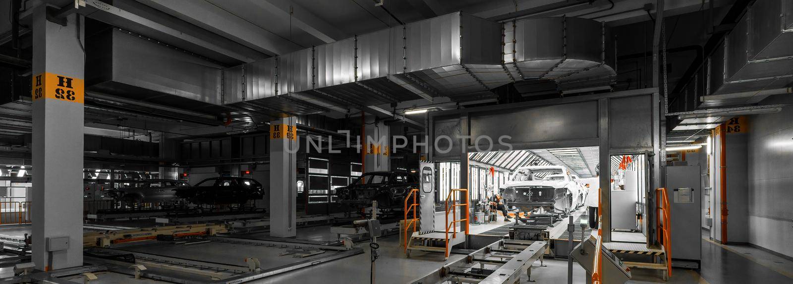 Panoramic dark photo of automobiles. Car bodies are on assembly line. Factory for production of cars. Modern automotive industry. Auto plant concept.