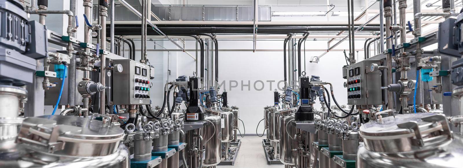 Panoramic photo of gray metal pipes and tanks. Chemistry and medicine production. Pharmaceutical factory. Interior of a high-tech factory, modern production.