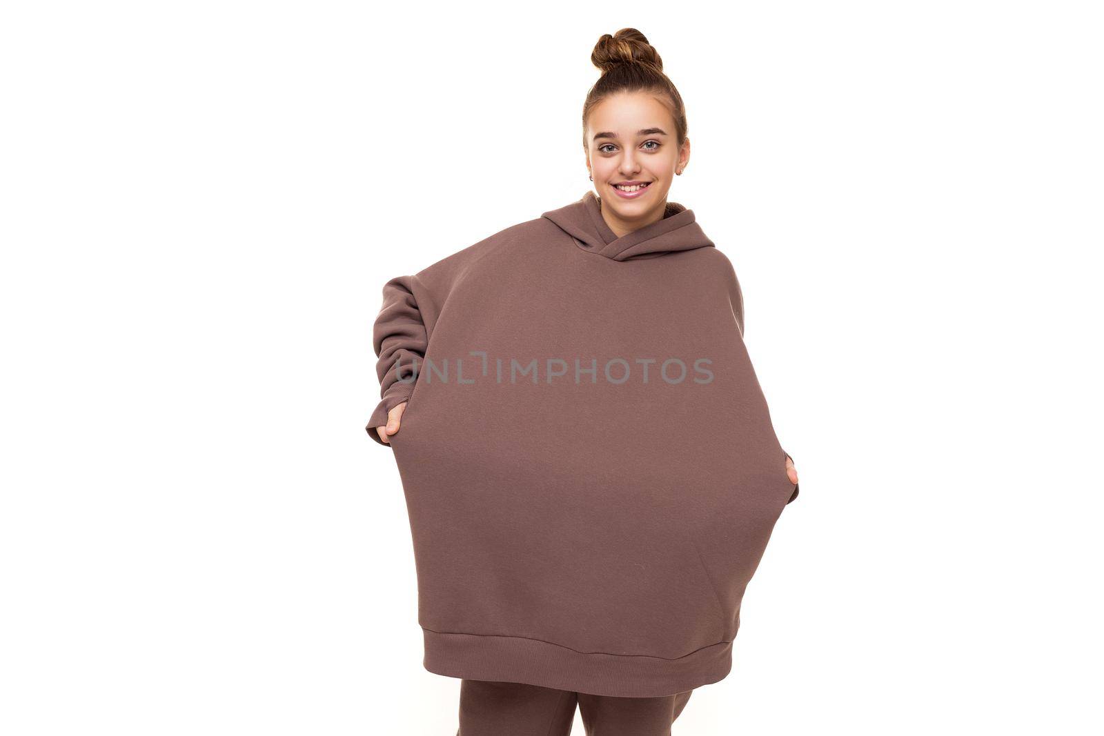 Photo of a beautiful cute girl with dark hair and a bun in a brown hoodie with a hood isolated on a white background with a place for text.