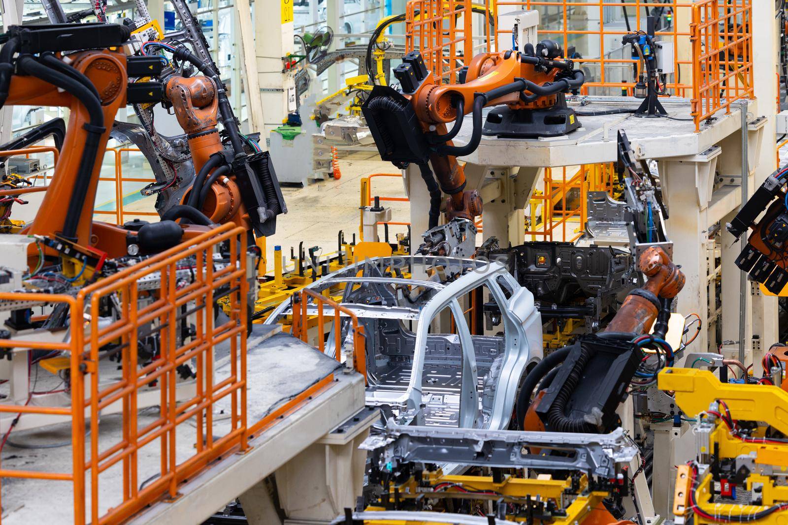 Photo of car bodies are on assembly line. Factory for production of cars. Modern automotive industry. Electric car factory, conveyor.