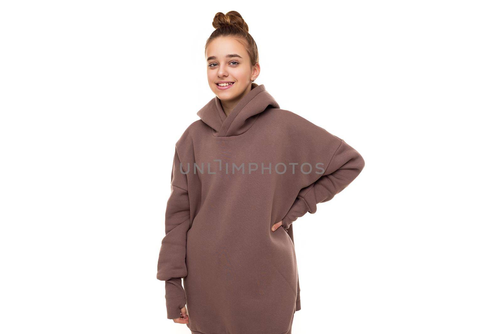 Photo of a beautiful cute smiling girl with dark hair and a bun in a brown hoodie with a hood isolated on a white background with a place for text.