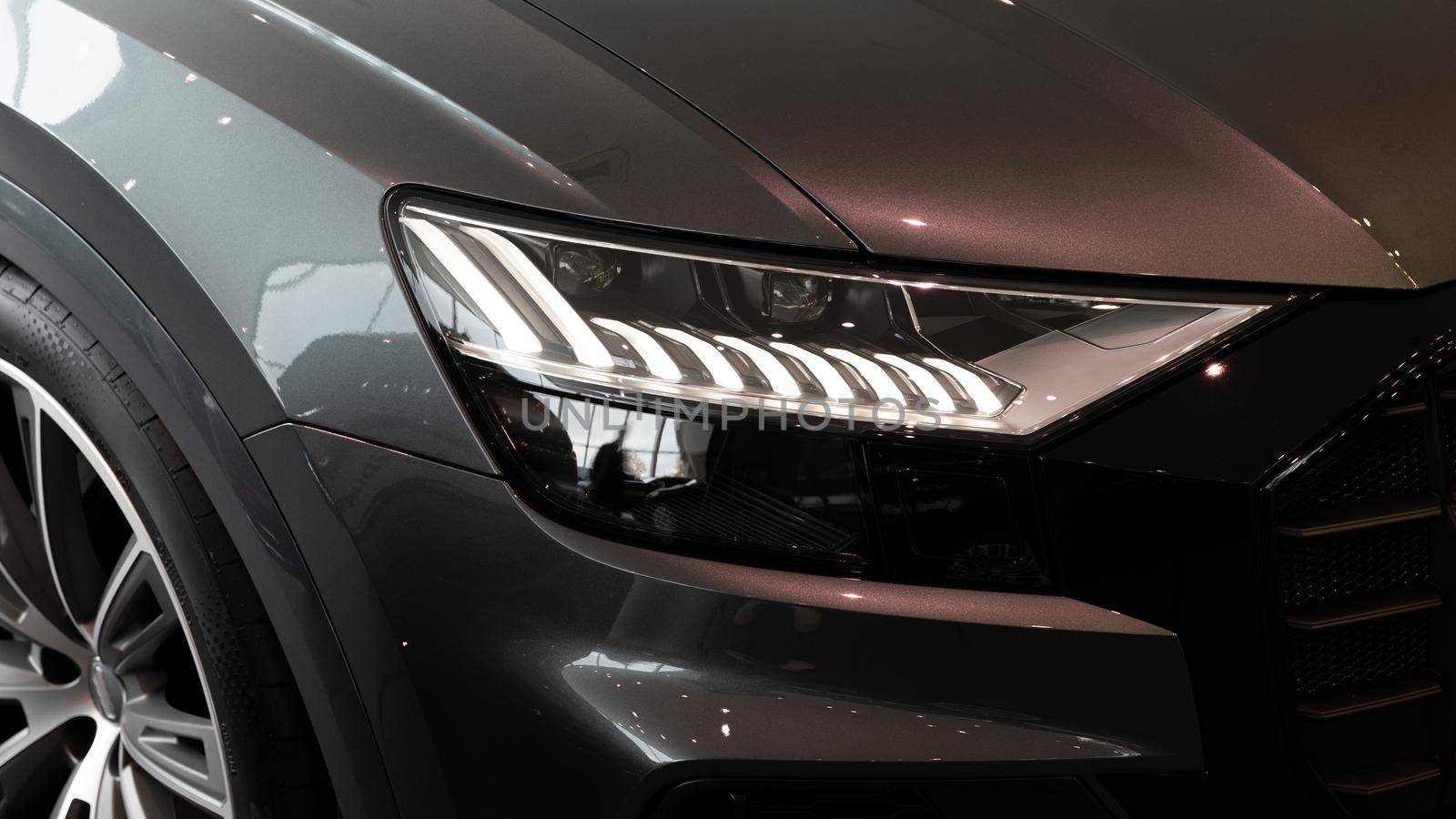 headlight of a gray modern car close-up in a car dealership.