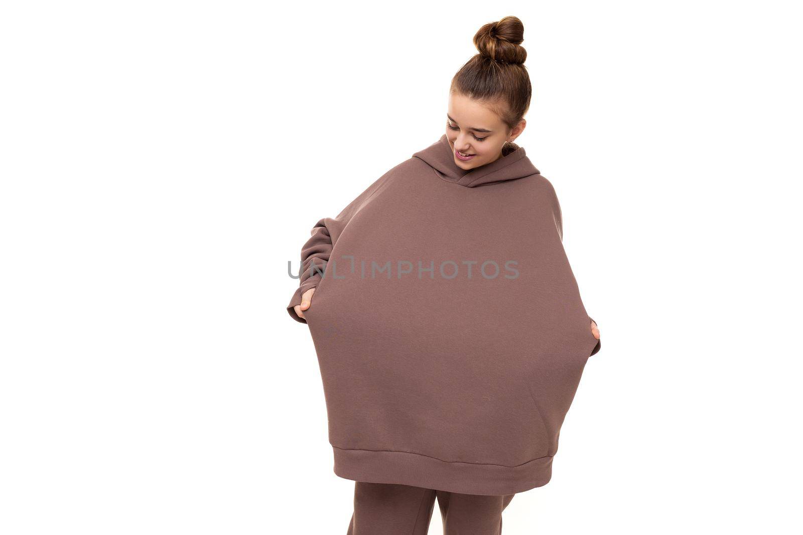 Photo of a beautiful cute girl with dark hair and a bun in a brown hoodie with a hood isolated on a white background with a place for text.