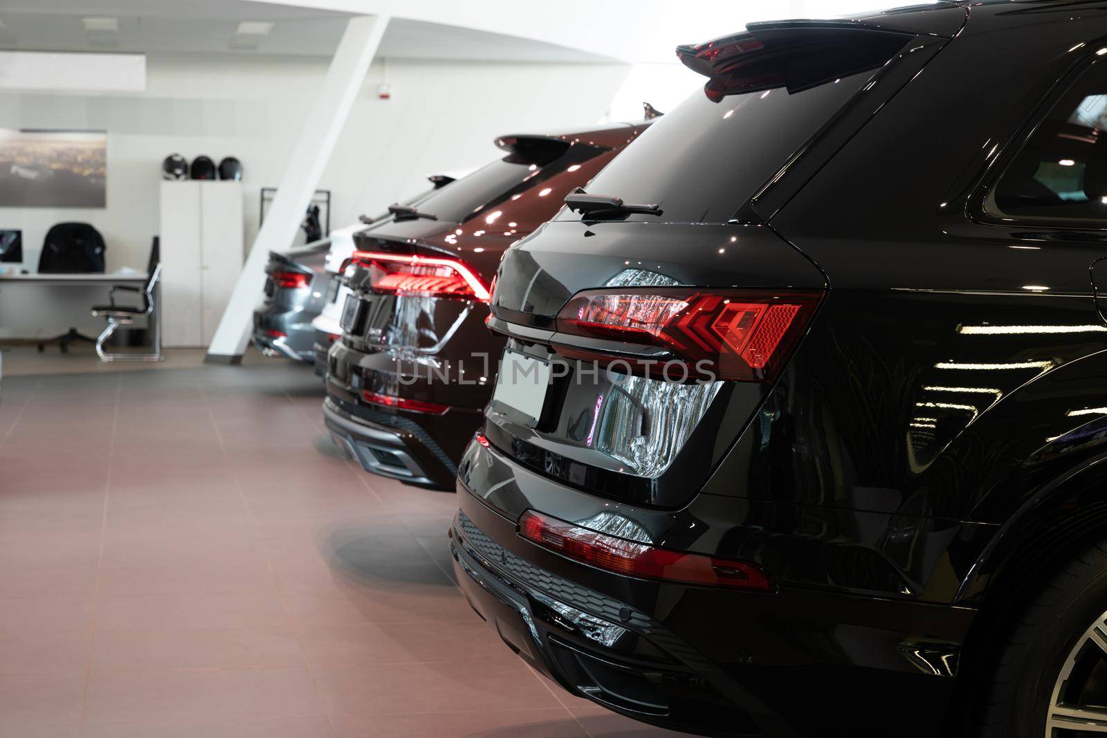 dealership car showroom of premium SUVs, cars in a row, rear view.
